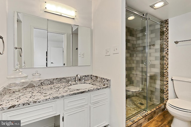 full bathroom with toilet, a shower stall, wood finished floors, and vanity