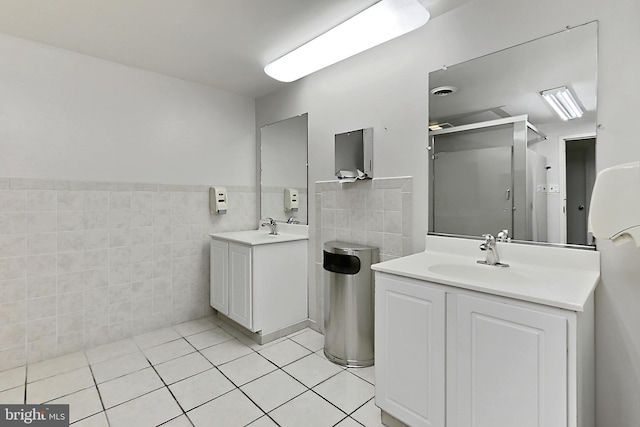 full bath featuring tile patterned flooring, a sink, a stall shower, and tile walls