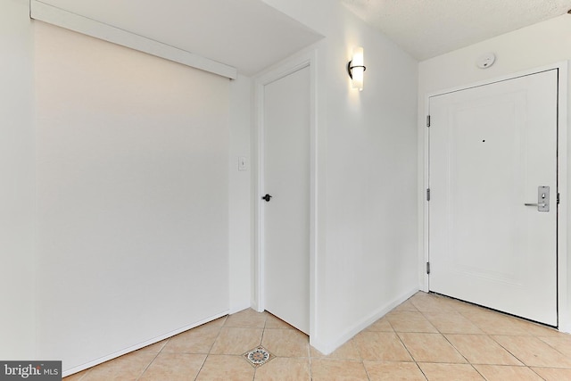 entrance foyer with light tile patterned floors and baseboards