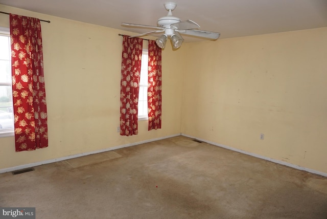 empty room featuring a wealth of natural light, carpet, and visible vents