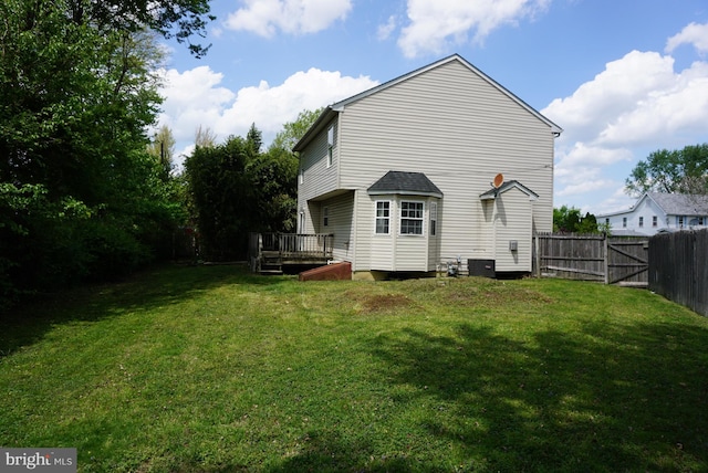 back of property featuring a lawn, a fenced backyard, a deck, and cooling unit