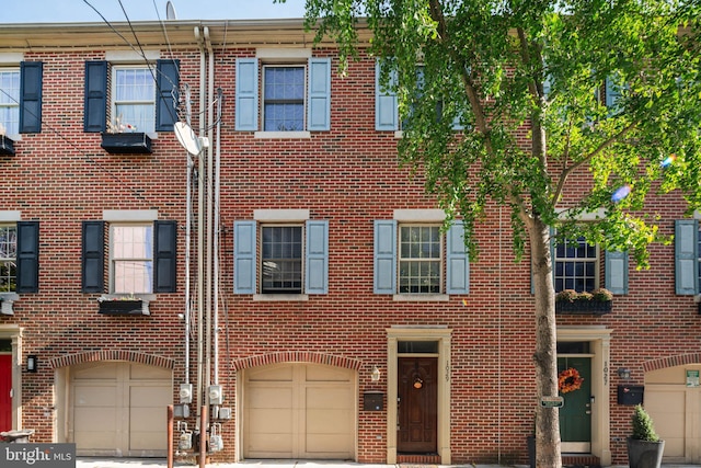 townhome / multi-family property with brick siding, driveway, and a garage