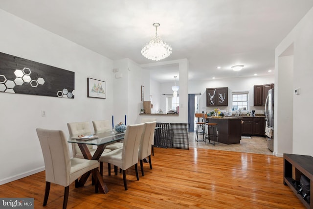 dining area with baseboards, a chandelier, and light wood-type flooring