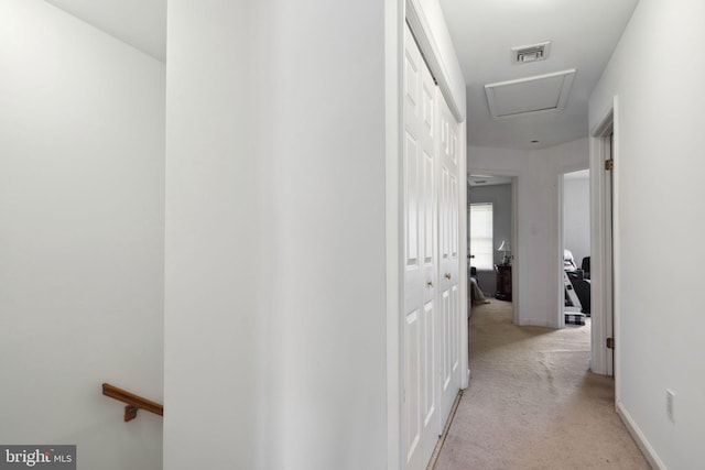 hall with light carpet, attic access, and visible vents