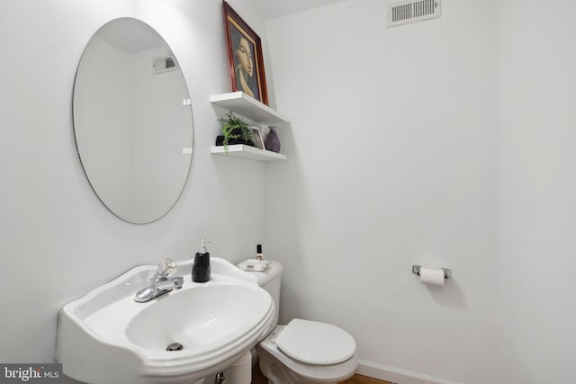 half bath with a sink, toilet, and visible vents