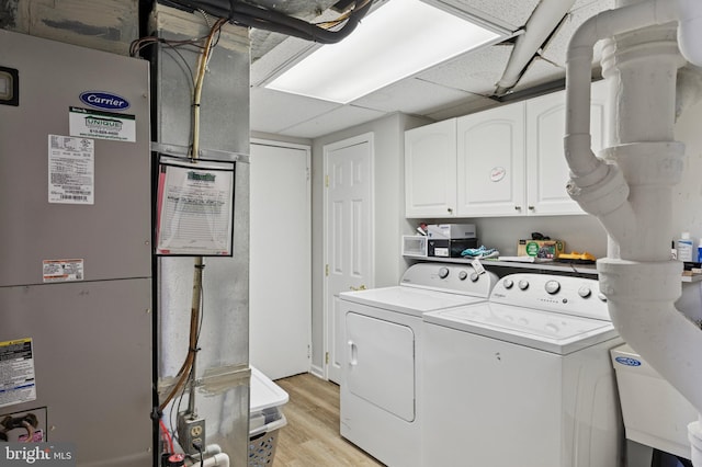 laundry room featuring cabinet space, washer and clothes dryer, light wood-style flooring, and heating unit