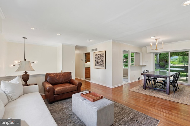 living room with a chandelier, wood finished floors, ornamental molding, baseboards, and recessed lighting