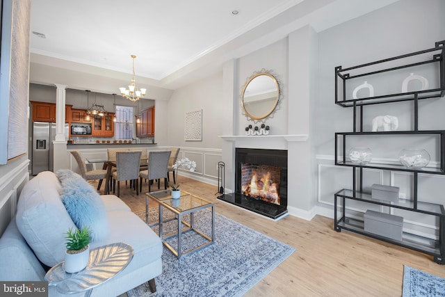 903 R St NW Unit 1, Washington, DC 20001 - living area with light wood-style floors, decorative columns, a warm lit fireplace, an inviting chandelier, and ornamental molding