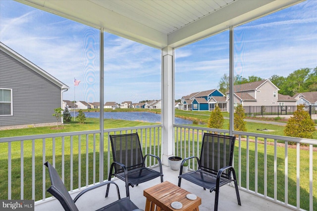 sunroom / solarium featuring a water view and a residential view