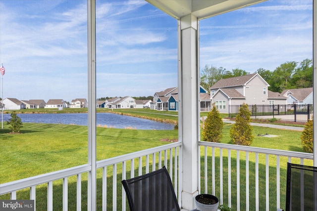 sunroom / solarium featuring plenty of natural light, a water view, and a residential view