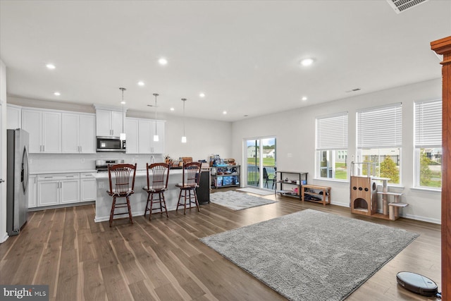 kitchen featuring an island with sink, a breakfast bar, stainless steel appliances, white cabinets, and recessed lighting