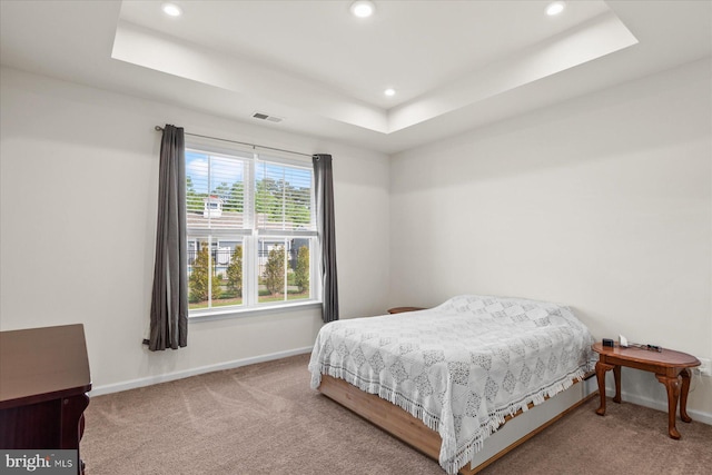 carpeted bedroom with baseboards, a raised ceiling, recessed lighting, and visible vents
