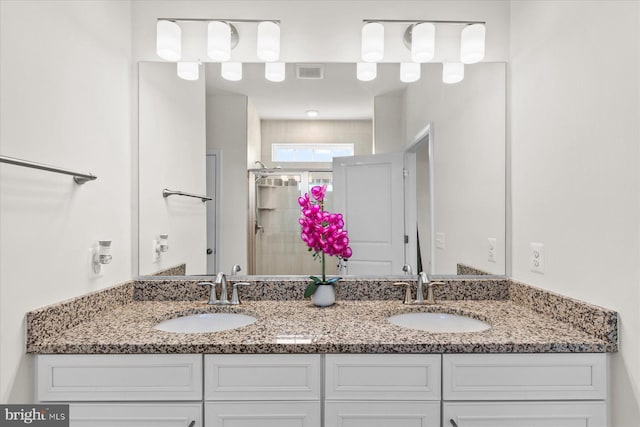 full bathroom featuring double vanity, visible vents, a stall shower, and a sink
