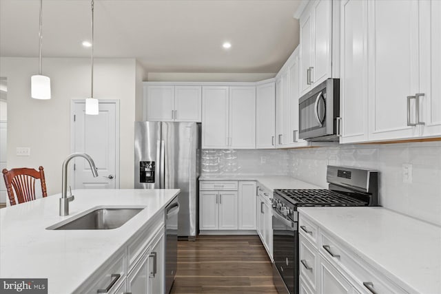kitchen featuring a sink, stainless steel appliances, white cabinets, dark wood-type flooring, and tasteful backsplash