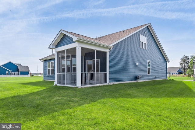 rear view of property featuring a sunroom, a shingled roof, and a lawn