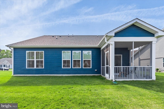 back of property featuring a sunroom, roof with shingles, and a lawn