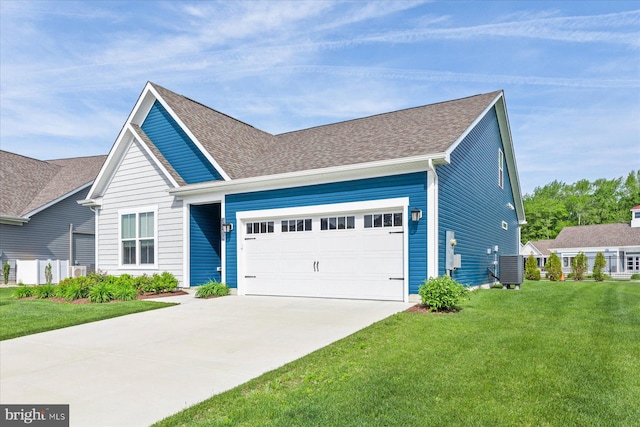 view of front facade with central air condition unit, roof with shingles, an attached garage, driveway, and a front yard
