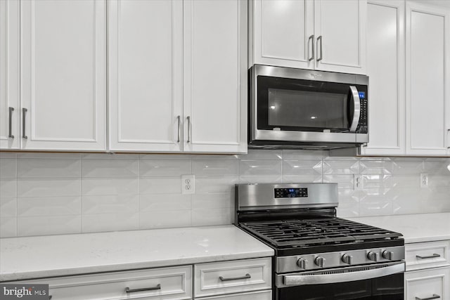 kitchen featuring stainless steel appliances, white cabinetry, and backsplash