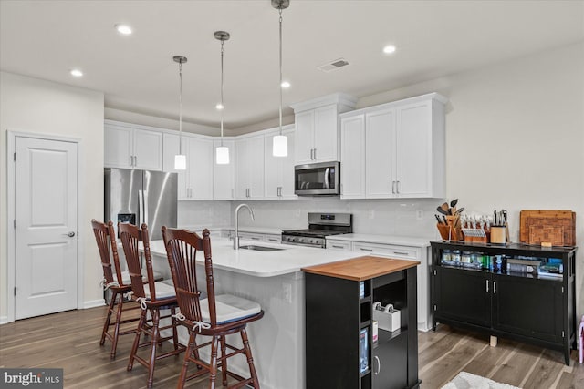 kitchen with appliances with stainless steel finishes, visible vents, wood finished floors, and a sink