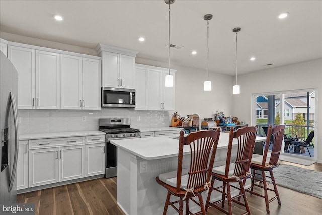 kitchen featuring stainless steel appliances, backsplash, light countertops, and dark wood-style floors