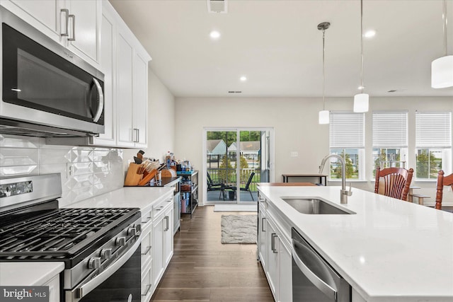 kitchen with visible vents, a sink, dark wood-type flooring, a kitchen island with sink, and appliances with stainless steel finishes