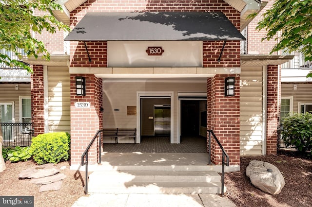 property entrance featuring elevator and brick siding