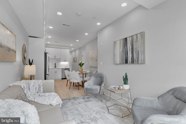 living area with recessed lighting, light wood-style flooring, and visible vents