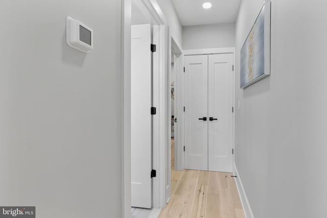corridor featuring baseboards and light wood-style flooring
