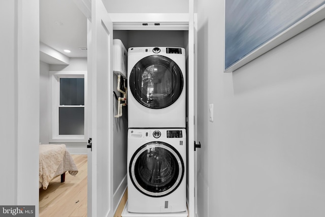 clothes washing area with laundry area, wood finished floors, baseboards, recessed lighting, and stacked washer / drying machine