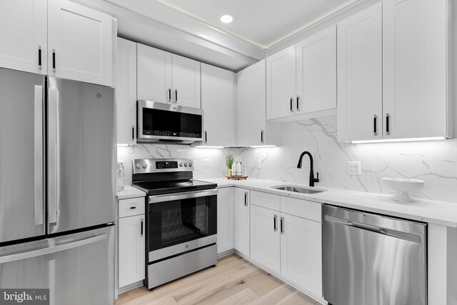 kitchen with white cabinets, appliances with stainless steel finishes, a sink, recessed lighting, and tasteful backsplash