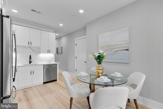 kitchen with visible vents, baseboards, a sink, light wood-style flooring, and stainless steel appliances