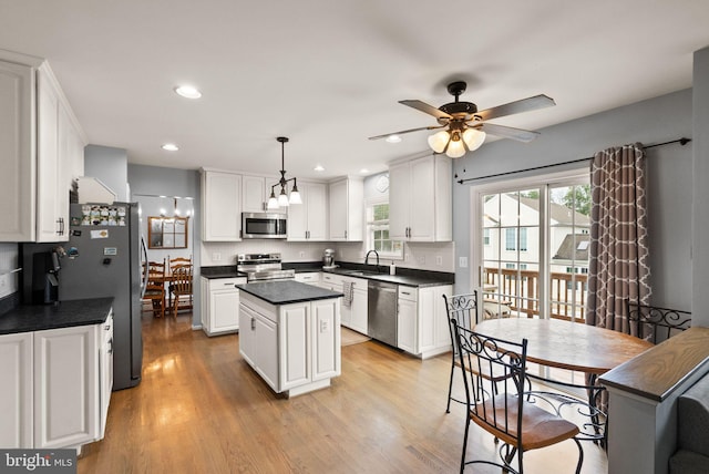 kitchen featuring dark countertops, appliances with stainless steel finishes, a center island, and a healthy amount of sunlight