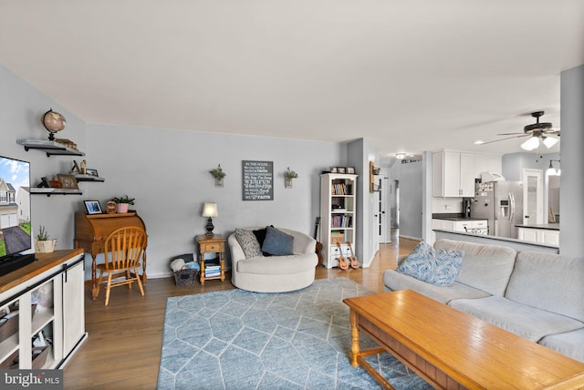 living room featuring baseboards, ceiling fan, and wood finished floors
