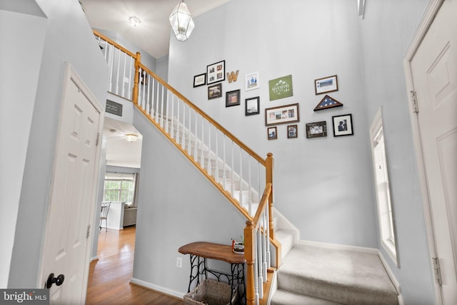 stairs featuring a high ceiling, baseboards, and wood finished floors