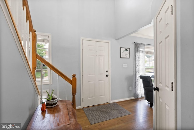 foyer featuring baseboards, stairs, wood finished floors, and a towering ceiling