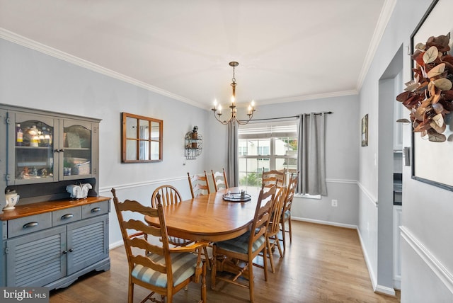 dining space with an inviting chandelier, ornamental molding, baseboards, and wood finished floors