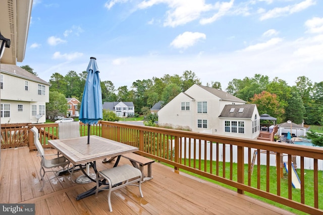 deck with a residential view, outdoor dining space, and a lawn