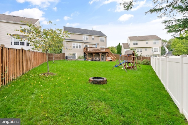view of yard with a playground, a fenced backyard, an outdoor fire pit, and a deck