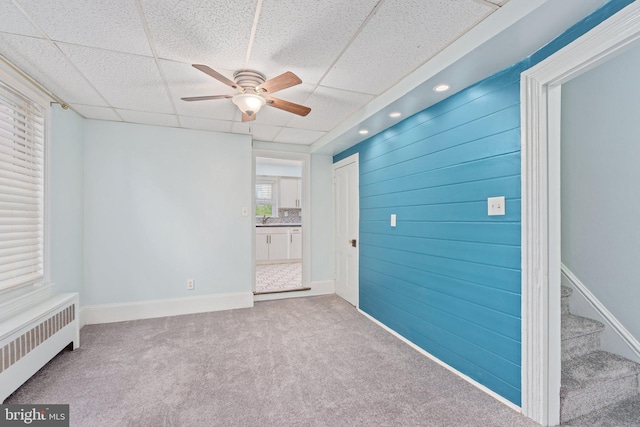 carpeted spare room with radiator, a ceiling fan, and baseboards