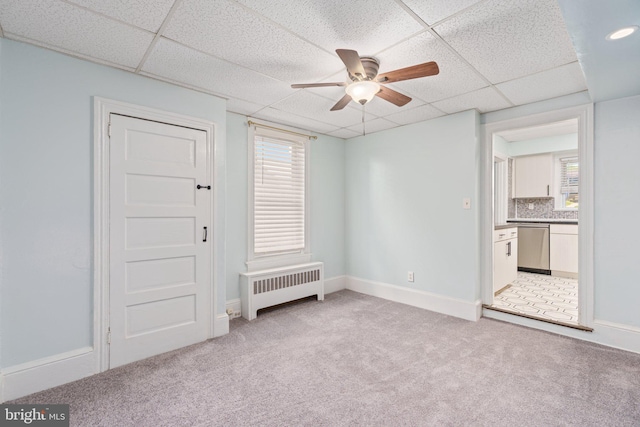 unfurnished bedroom featuring radiator heating unit, a drop ceiling, carpet flooring, baseboards, and ensuite bath