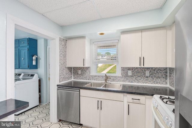 kitchen featuring a sink, appliances with stainless steel finishes, a paneled ceiling, tasteful backsplash, and washer and clothes dryer