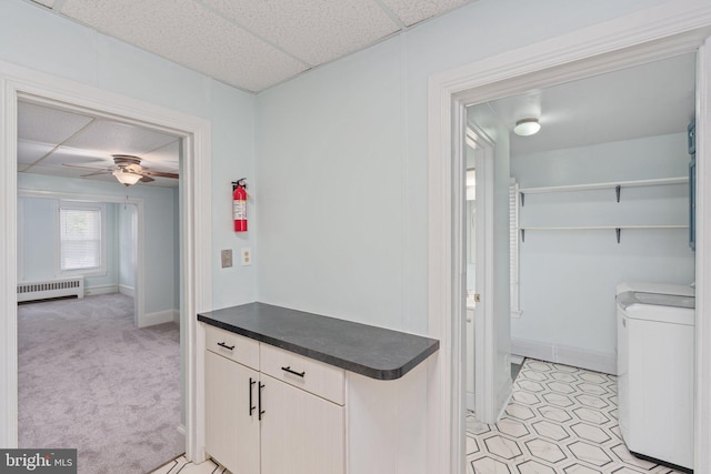 laundry room with washing machine and dryer, radiator heating unit, baseboards, a ceiling fan, and light carpet