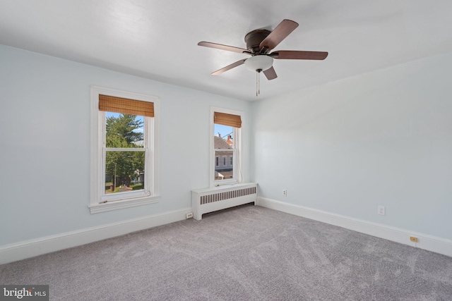carpeted empty room featuring radiator heating unit, ceiling fan, and baseboards