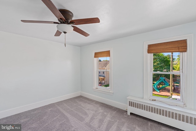 empty room with radiator, baseboards, carpet flooring, and a ceiling fan