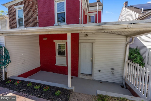 doorway to property with brick siding and fence