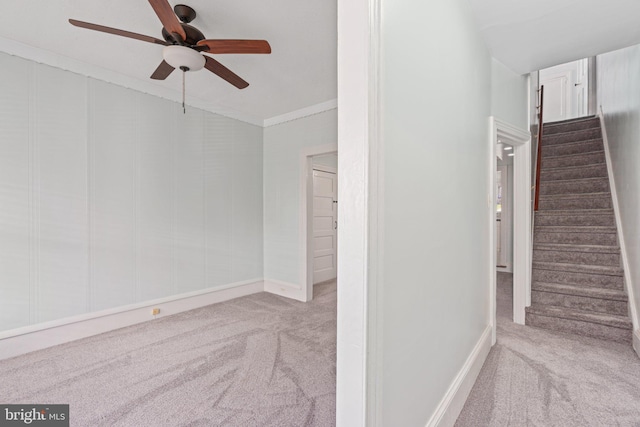 stairs with carpet, a ceiling fan, baseboards, and ornamental molding