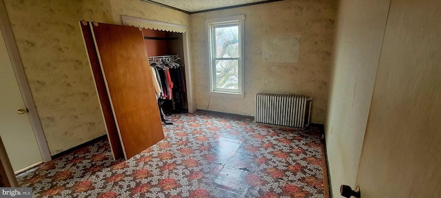 unfurnished bedroom featuring tile patterned floors, a closet, ornamental molding, and radiator heating unit