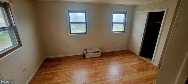 unfurnished bedroom with light wood-type flooring, baseboards, a closet, and crown molding