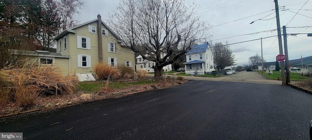 view of street featuring traffic signs, street lights, curbs, and a residential view