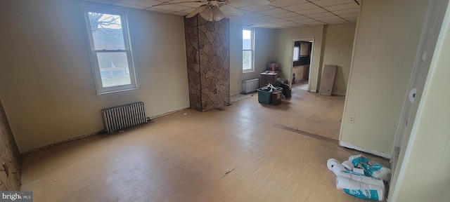 unfurnished room with a drop ceiling, ceiling fan, light wood finished floors, and radiator heating unit